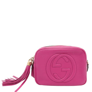 A bright pink leather crossbody bag with an embossed interlocking G logo, featuring a matching pink tassel charm and gold-tone hardware, set against a plain white background.