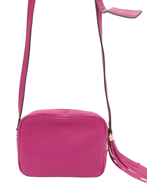 A bright pink textured leather crossbody bag with a matching pink strap and a tassel detail, shown against a plain white background.