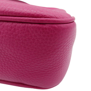 A close-up shot of a vibrant magenta pebbled leather bag corner on a clean white background.
