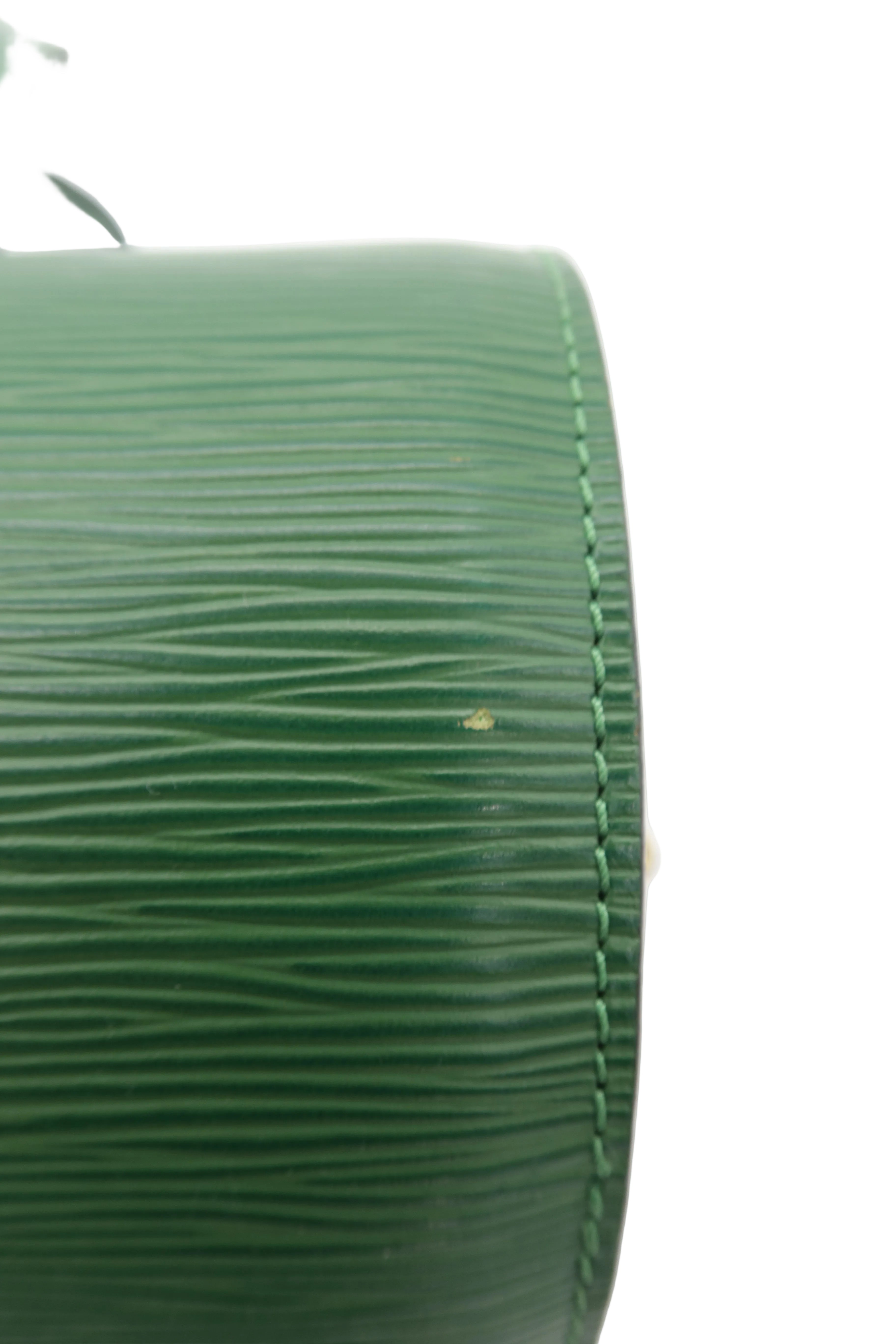 Close-up of a green textured leather bag corner with fine stitching on a white background.