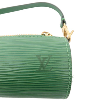 A close-up of a green textured leather pouch or clutch with a gold zipper and a matching green strap, featuring an embossed LV logo on a white background.