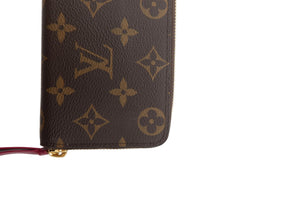 A close-up of a Louis Vuitton monogram zip-around wallet in brown coated canvas with gold-tone hardware, shown on a plain white background.
