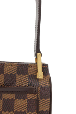 Close-up of a Louis Vuitton handbag in the Damier Ebene checkered canvas, featuring a brown leather strap with a gold-tone metal hardware clasp on a light gray background.