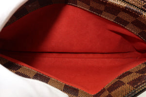 Close-up of the interior of a handbag or pouch, showing a bright red suede-like lining and a brown and beige checkered patterned fabric edge.