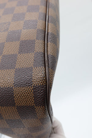 Close-up of a brown and tan checkerboard patterned material with a dark brown edge, shown against a light gray background.