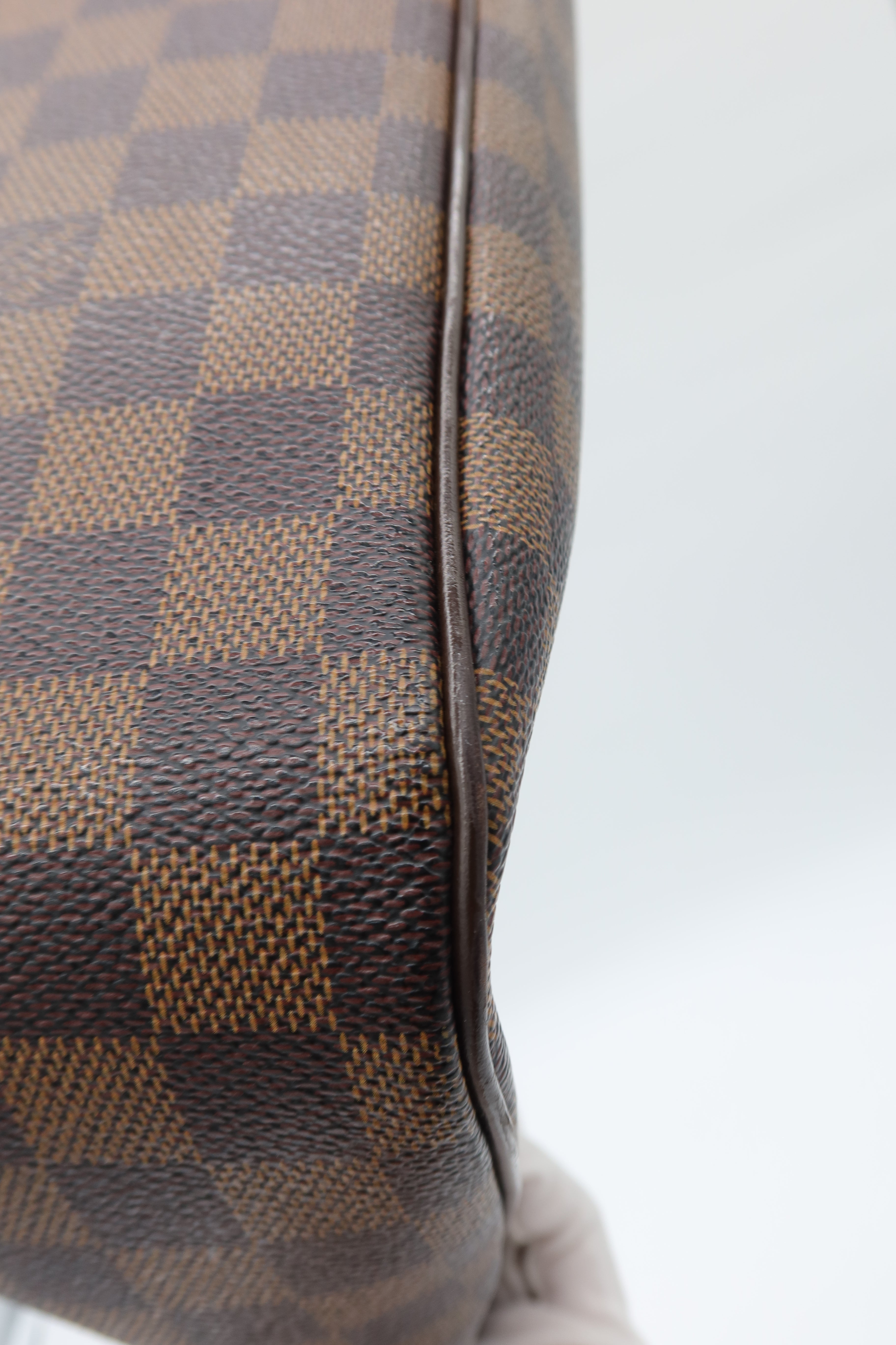 Close-up of a brown and tan checkerboard patterned material with a dark brown edge, shown against a light gray background.