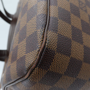 Close-up of a Louis Vuitton handbag in Damier Ebene canvas, showing the classic brown and beige checkered pattern and dark brown leather trim.