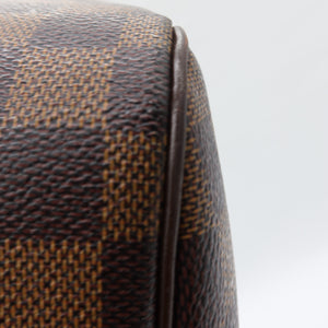Close-up of a brown and tan checkered leather product corner with a dark brown edge seam against a light gray background.