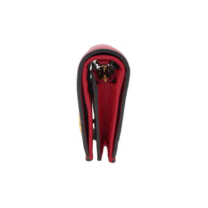 A close-up side view of a red leather wallet or card holder with black trim and a gold-tone metal clasp, set against a plain white background.