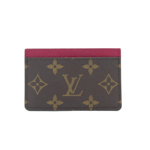 A Louis Vuitton monogram card holder with a dark brown coated canvas body, gold-tone LV logo and floral motifs, and a contrasting dark red leather top border, shown on a clean white background.