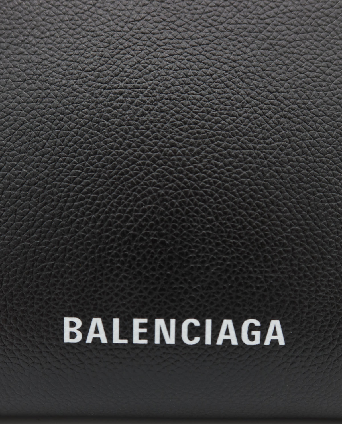 Close-up of a black pebbled leather Balenciaga pouch or wallet with the brand name 'BALENCIAGA' printed in white capital letters on the front.