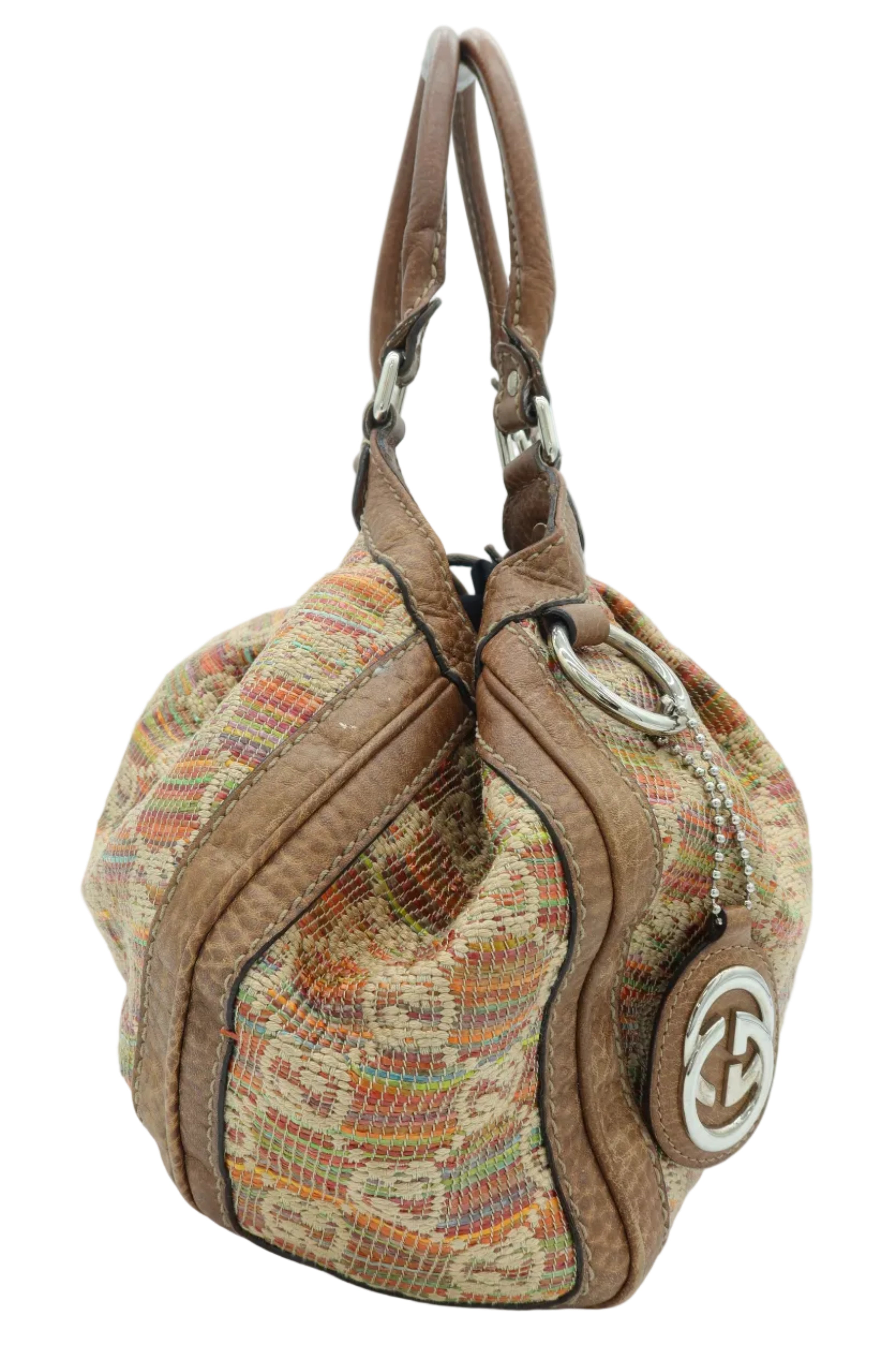 A Gucci shoulder bag featuring a brown leather trim and handle, combined with a multicolor woven canvas body. The iconic interlocking GG logo is visible on the side leather patch.