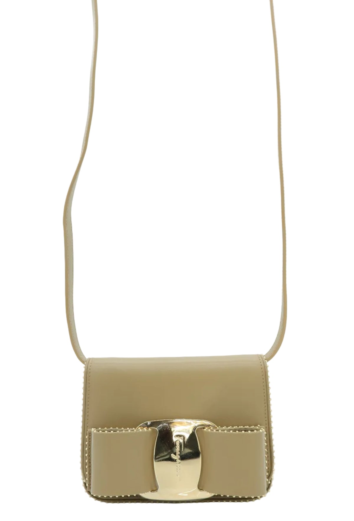 A small structured shoulder bag in light beige leather with a prominent gold-tone bow detail and strap on a light blue background.