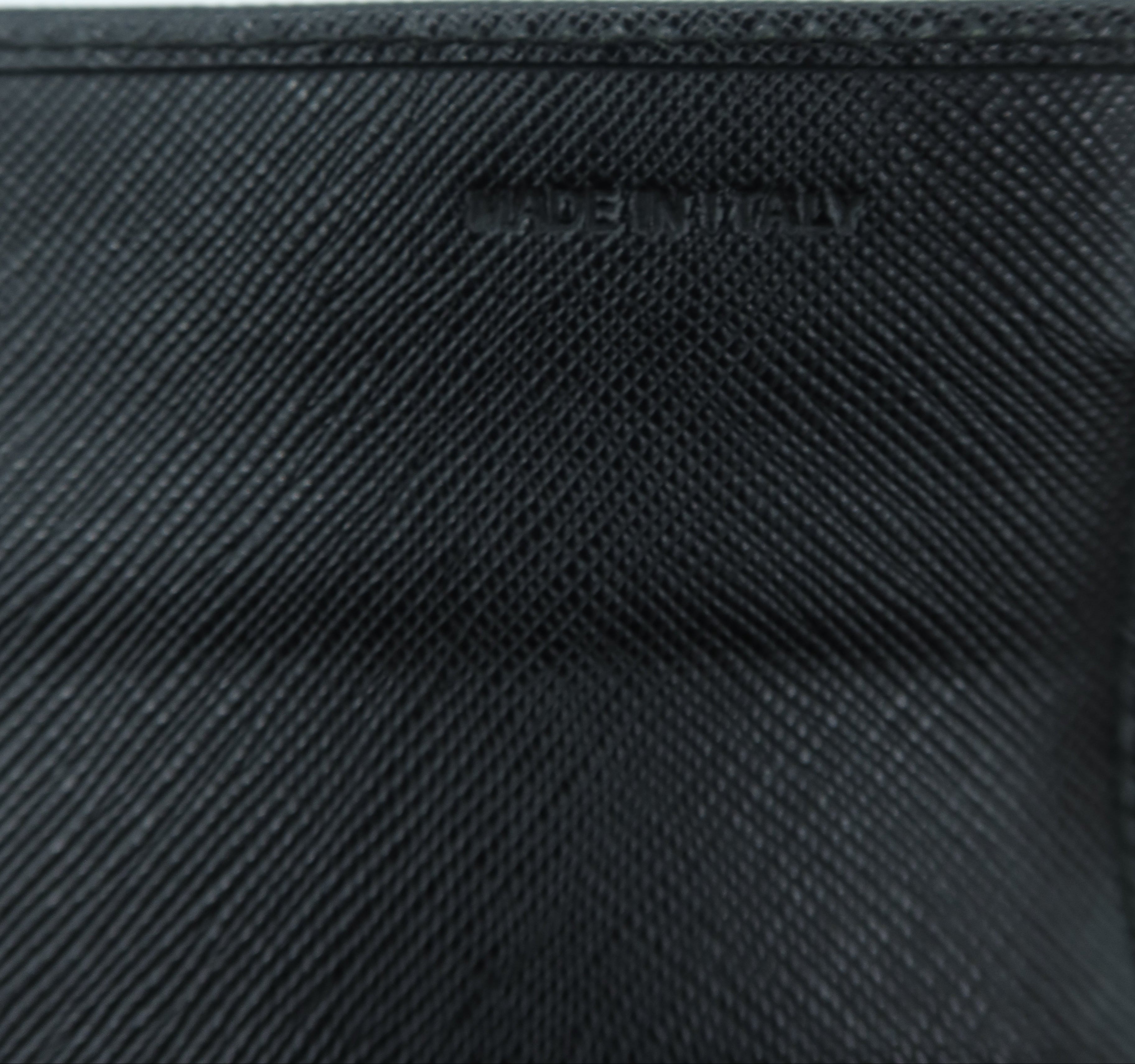 Close-up of a black textured leather pouch or wallet with a debossed logo on a light gray background.
