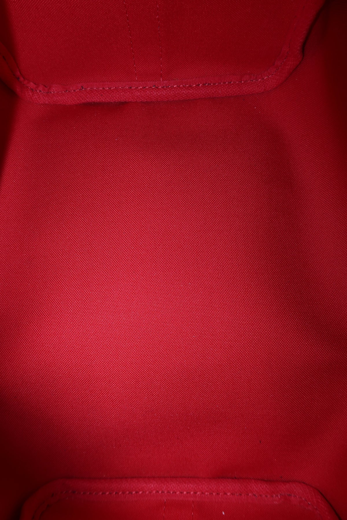 Close-up of a red fabric surface with visible stitched panel seams and a fine woven texture.