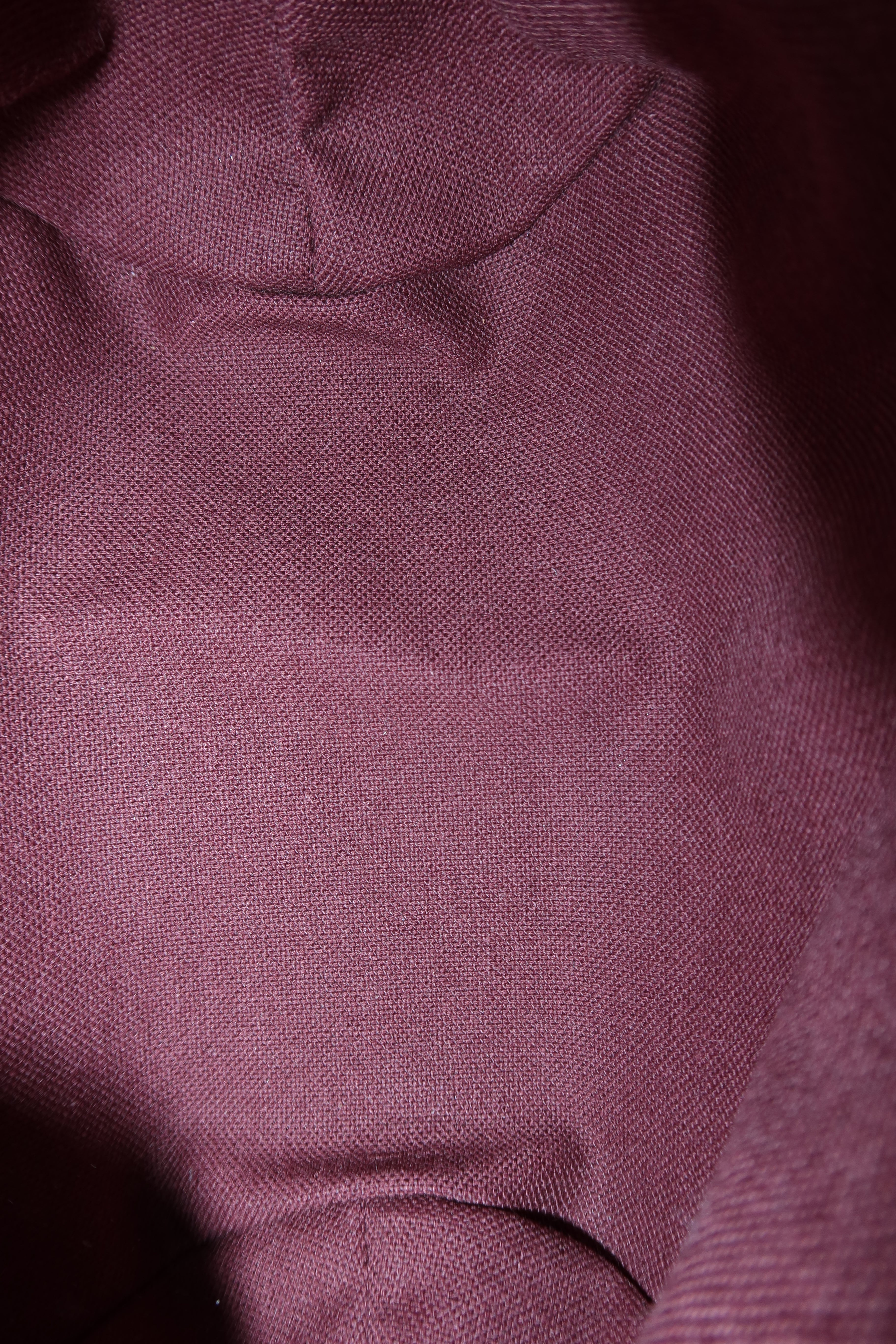 A close-up of textured fabric in a muted dusty rose or mauve color, showing the weave and soft folds.