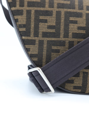 Close-up of a Fendi shoulder bag featuring the signature brown and black FF monogram canvas and a dark strap with a silver buckle, set against a plain white background.