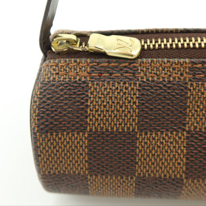 Close-up of a Louis Vuitton cylindrical bag in the Damier Ebene checkered canvas, featuring a gold-tone zipper with a gold-tone LV logo pull and a dark brown leather strap against a white background.