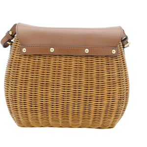 A brown and tan woven wicker shoulder bag with a smooth brown leather flap and gold-tone metal rivets, shown against a plain white background.