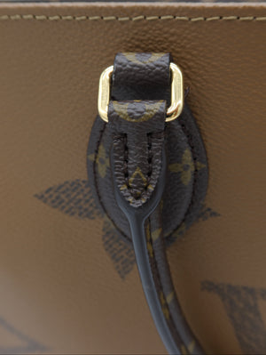 Close-up detail of a Louis Vuitton monogram handbag showing the dark brown coated canvas strap with gold-tone hardware and a glimpse of the tan Vachetta leather body.