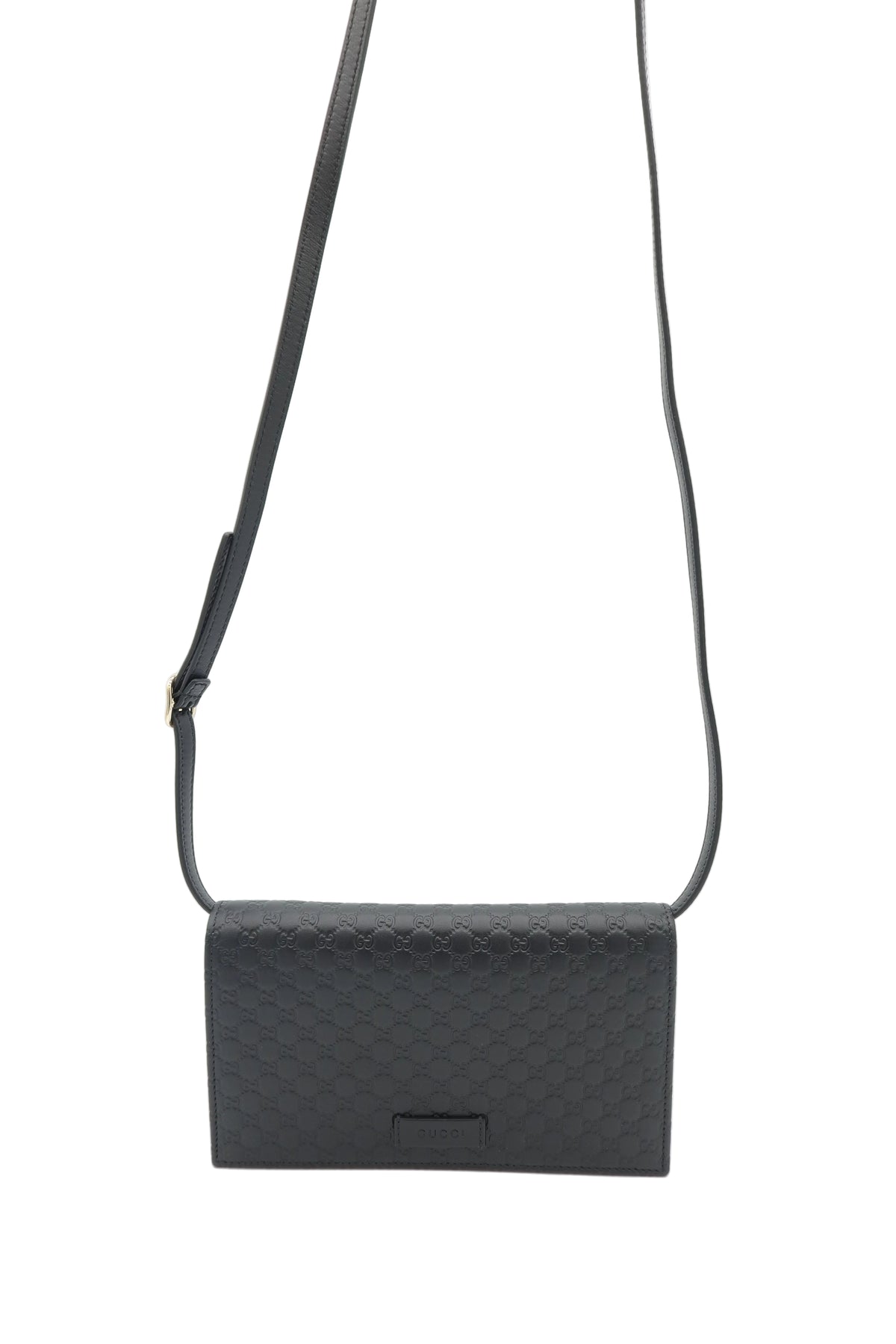 A black leather crossbody bag with a textured diamond pattern, featuring a thin black strap and a small rectangular metal plaque on the front, set against a plain white background.