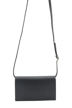 Black textured leather crossbody bag with a long shoulder strap, shown against a plain white background.