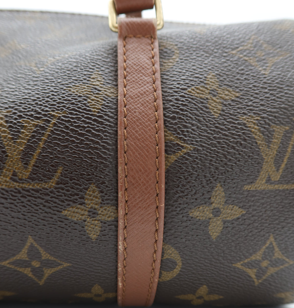 Close-up of a Louis Vuitton monogram canvas bag with a brown leather strap and gold-tone hardware, showing the classic LV monogram pattern.
