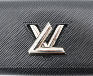 A close-up of a black textured leather Louis Vuitton wallet or clutch featuring the iconic silver-tone LV logo on the front.