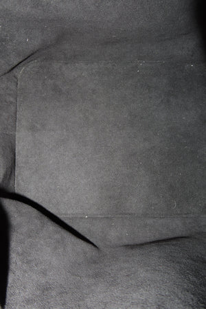 Close-up of a dark gray suede or microfiber fabric surface with a stitched rectangular pocket and a dark seam running diagonally.