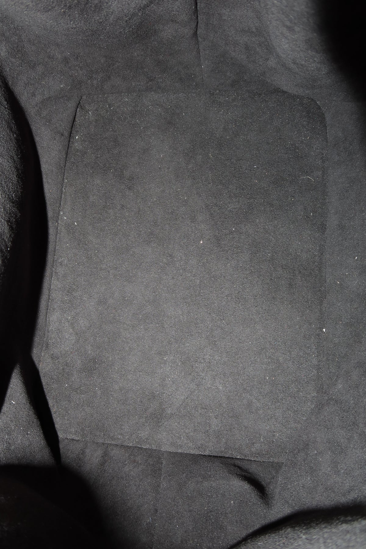 A close-up view of a dark gray suede or microfiber fabric surface with a rectangular patch of the same material in the center.