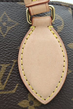 Close-up of a Louis Vuitton monogram handbag showing the signature brown coated canvas with gold-tone LV monogram pattern, a beige leather strap, and a matching beige leather teardrop-shaped tag with yellow contrast stitching.