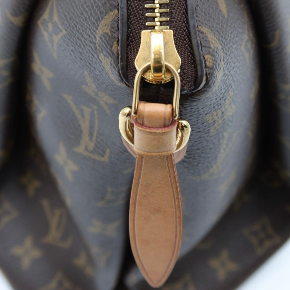 Close-up of a Louis Vuitton monogram canvas handbag with a gold-tone zipper and tan leather pull tab.