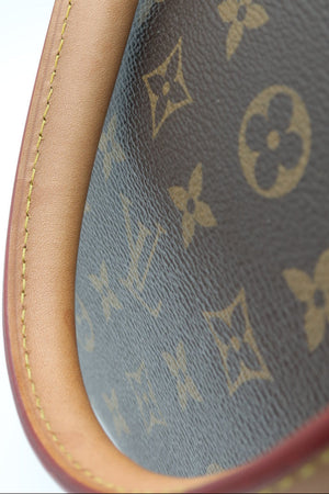 Close-up of a Louis Vuitton handbag corner showing the brown monogram canvas and tan leather trim against a white background.