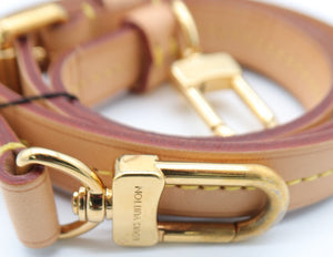 A close-up of a Louis Vuitton tan leather strap with gold-tone hardware, featuring a prominent D-ring and a buckle engraved with the Louis Vuitton brand name.