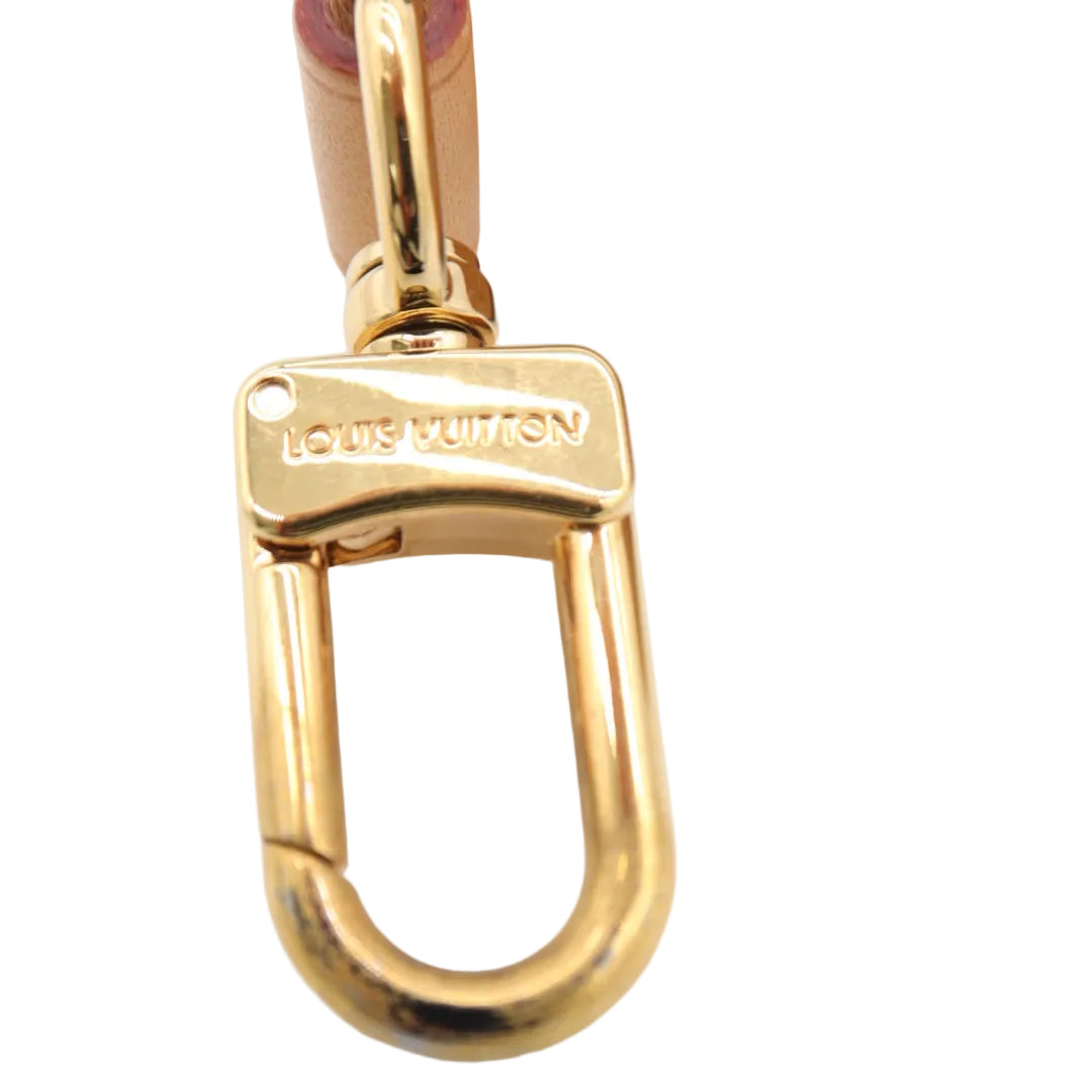 Close-up of a gold-tone metal carabiner clasp engraved with 'LOVE LUIVRETON' on a light-colored surface, with part of a tan leather strap visible at the top.