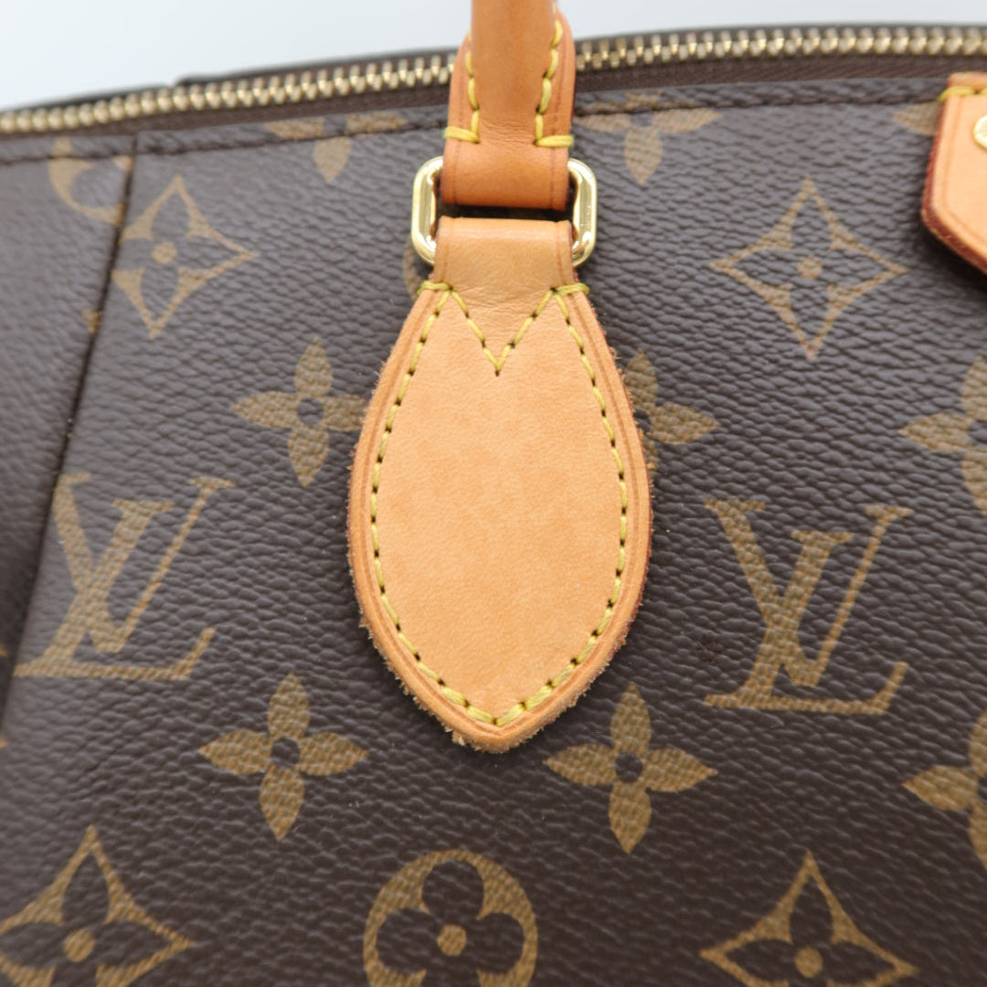 Close-up of a Louis Vuitton monogram canvas handbag with a tan leather handle and gold-tone hardware.
