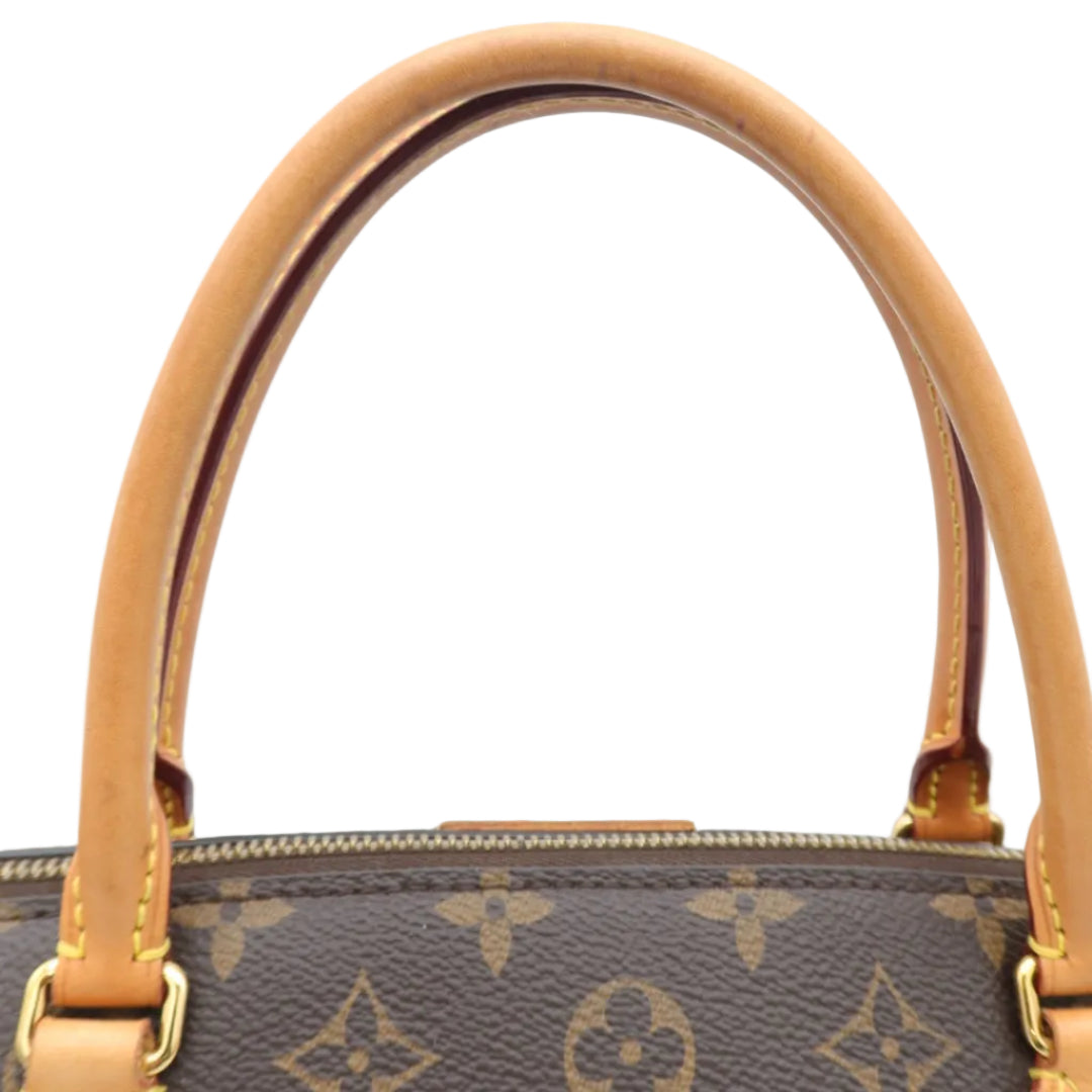 Close-up of a Louis Vuitton handbag handle on a plain white background. The handle is made of tan vachetta leather, attached to a brown monogram canvas body with gold-tone hardware.