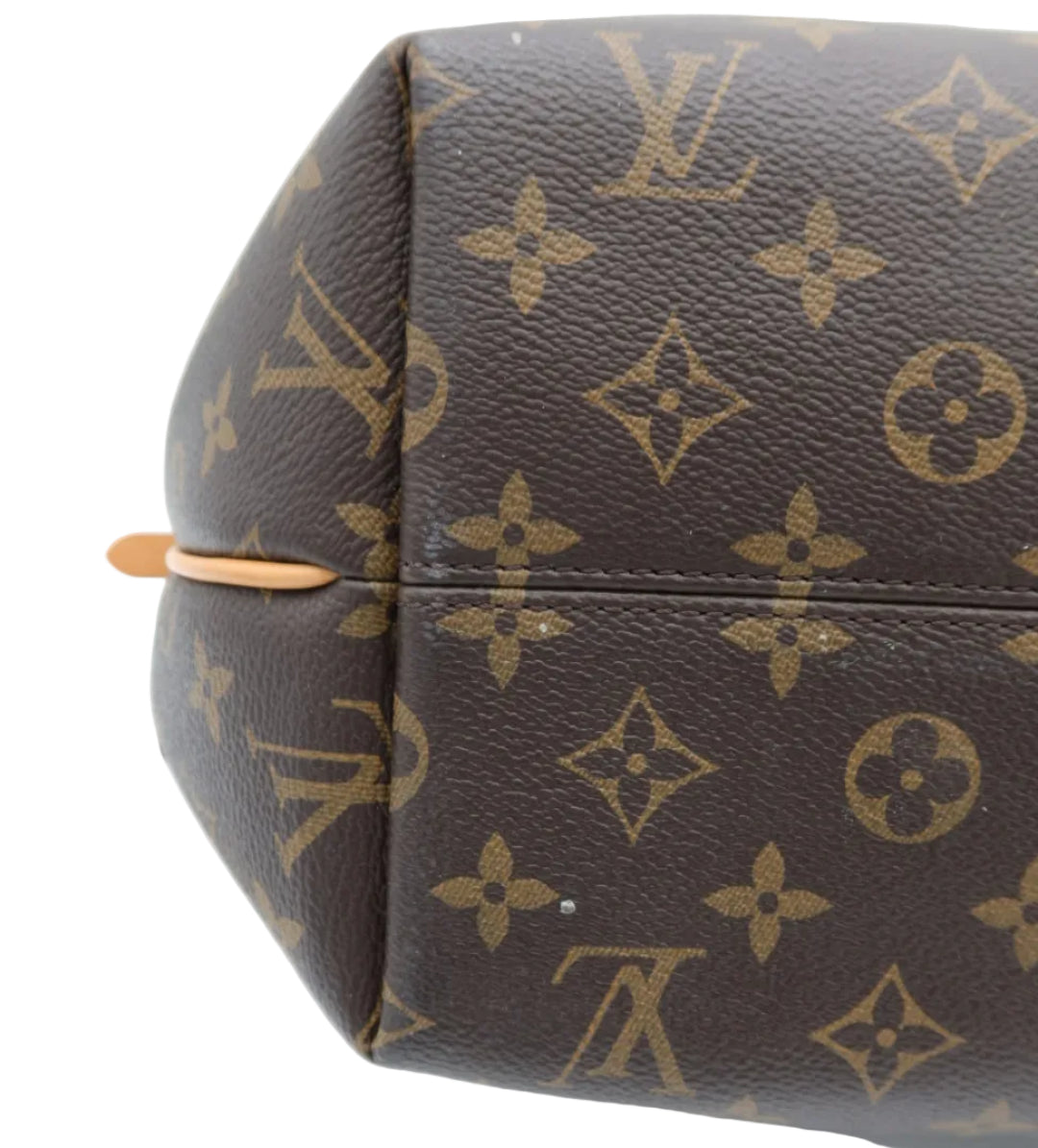 Close-up of a Louis Vuitton monogram canvas bag corner showing the classic brown and tan LV pattern with a small tan leather pull tab on a white background.