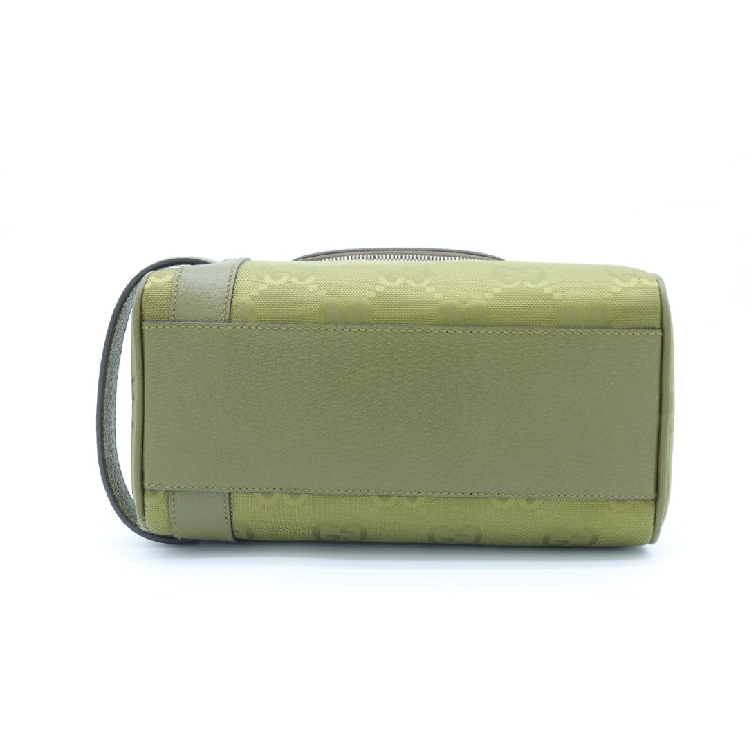 An olive green cylindrical handbag with a textured leather front panel, a subtle embossed monogram pattern, and a dark strap, shown against a plain white background.