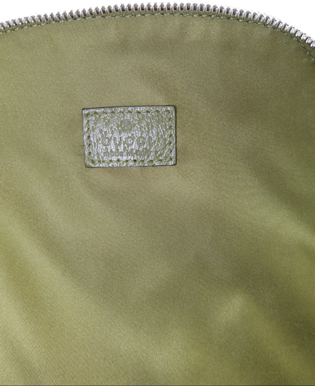 Close-up of a metallic olive green nylon bag with a silver zipper and a textured silver brand patch on a white background.