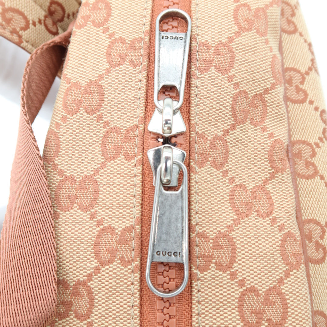 Close-up of a beige and pink GG Supreme canvas bag with a silver-tone metal zipper pull engraved with 'GUCCI'.