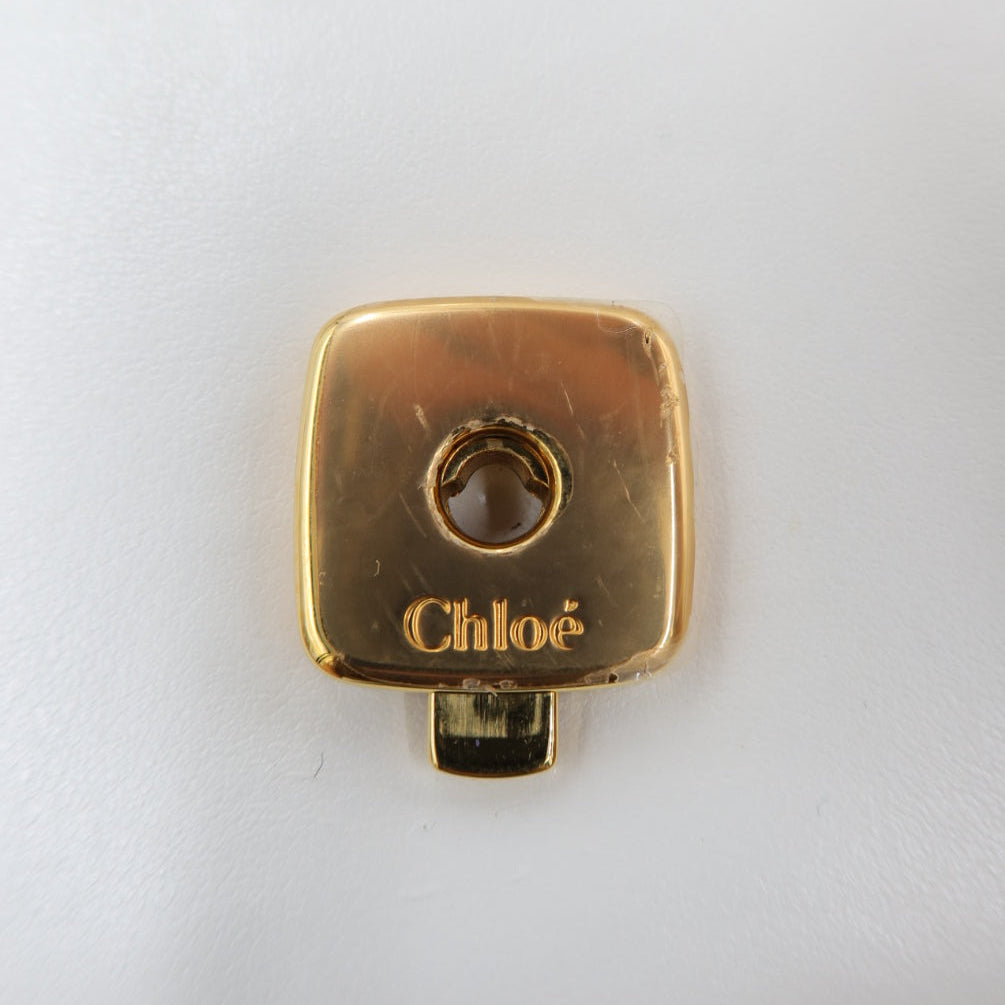 A gold-tone metal hardware piece with the brand name 'Chloé' engraved on it, set against a plain white background.