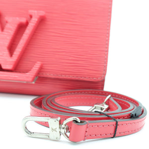 A close-up of a pink textured leather shoulder strap with silver-tone hardware, shown in front of a matching pink leather bag on a white background.