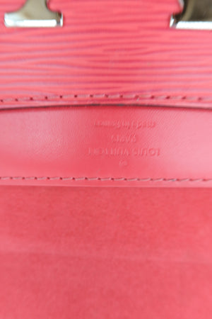 Close-up detail of a pink Louis Vuitton handbag showing the textured Epi leather strap, fine stitching, and embossed brand lettering on the leather tab.