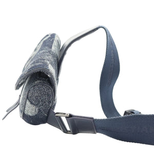 A close-up of a dark blue fabric strap and matching cylindrical accessory with a textured pattern, photographed on a clean white background.