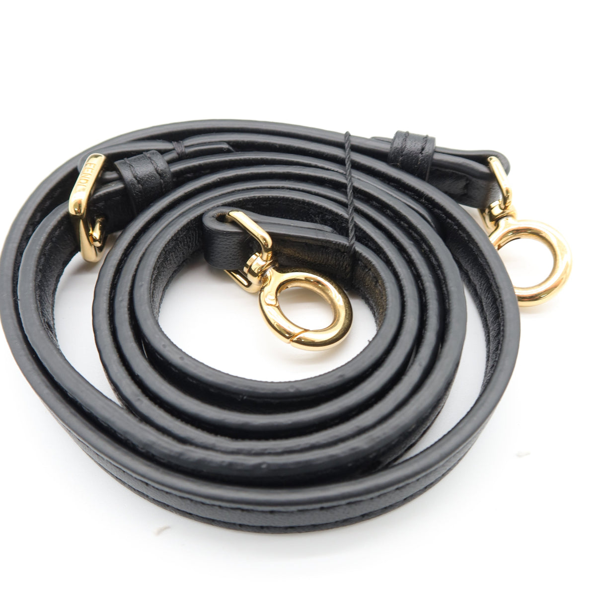 A black leather shoulder strap coiled on a white background, featuring gold-tone metal hardware including rings and clips.