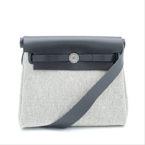 A structured shoulder bag with a light gray textured body, a dark gray leather top flap, and a matching gray strap, shown against a plain white background.