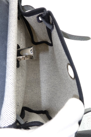 Close-up of the interior of a gray canvas bag with black trim, metal grommets, and a white mesh lining.