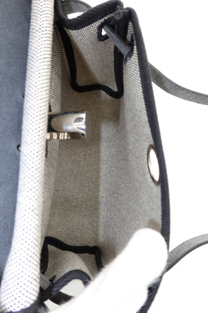 Close-up of the interior of a gray woven tote bag with black trim, metal grommets, and a white textured fabric panel.
