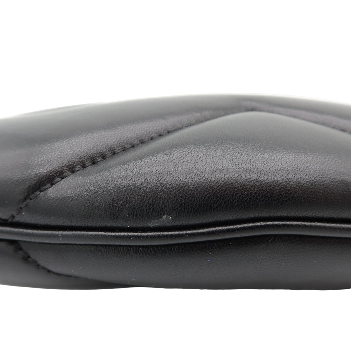 Close-up of a black leather pouch or clutch showing the quilted stitching and textured leather surface against a white background.